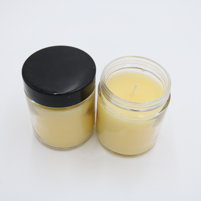La mano perfumada de la vela del tarro de cristal amarillo de la verbena del limón vertió velas de la soja con la tapa negra